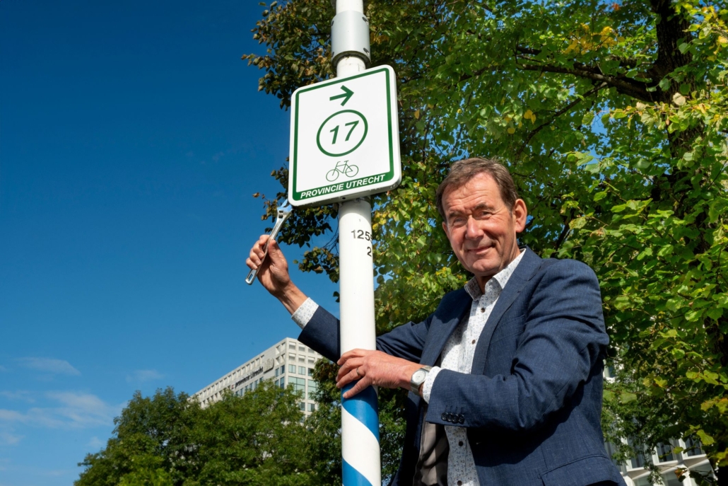 Gedeputeerde Rob van Muilekom plaatst symbolisch het eerste routebord van het vernieuwde recreatief fietsroutenetwerk.